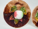 two decorative plates with fruit on them on a white surface
