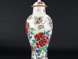 un vase blanc et rouge orné de fleurs, posé sur un fond noir