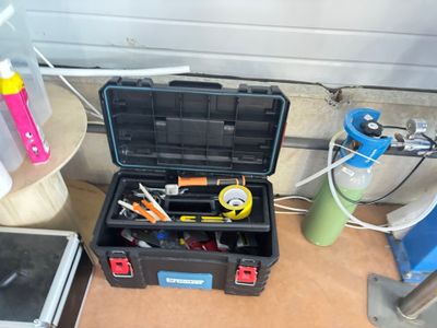 une boîte à outils contenant des outils, posée sur le sol