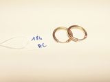 two gold rings on a white surface with a price tag