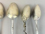 four spoons are lined up in a row on a table