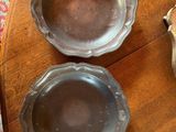 three silver dishes on a wooden table with a red and white rug