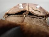 a brown leather wallet with two silver studs on it