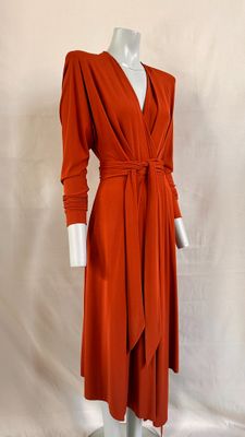 an orange dress on a mannequin stand with a white mannequin behind it