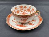 an orange and white cup and saucer on a black table