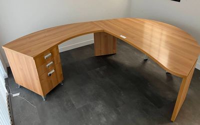 a large wooden desk with two drawers in the corner