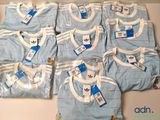 une pile de vêtements de bébé bleus et blancs posée sur une table