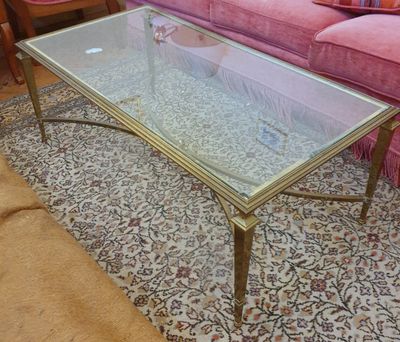 une table basse en verre posée sur un tapis, devant un canapé rose