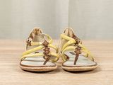 yellow and brown sandals on a wooden table with a curtain in the background
