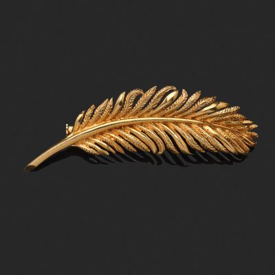 un gros plan d'une broche en feuille d'or sur fond noir