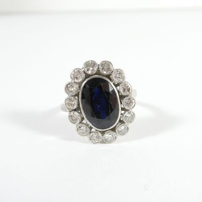 gros plan d'une bague avec une pierre bleue entourée de diamants