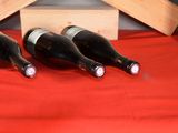 three bottles of wine sitting on a red table cloth