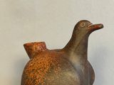 a bird shaped vase sitting on a stand on a white surface