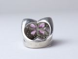 a close up of a silver ring with a pink flower inside of it