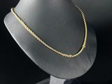 un collier en or posé sur un support de mannequin devant un fond noir