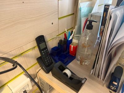 a cell phone on a desk with a lot of office supplies