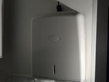 un distributeur de papier essuie-tout blanc fixé au mur au-dessus d'un lavabo