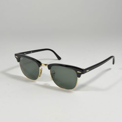 une paire de lunettes de soleil noires et dorées sur fond blanc