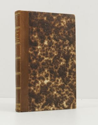 un vieux livre à la couverture marron posé sur une table blanche