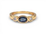 une bague en or jaune sertie d'un saphir bleu et de trois diamants