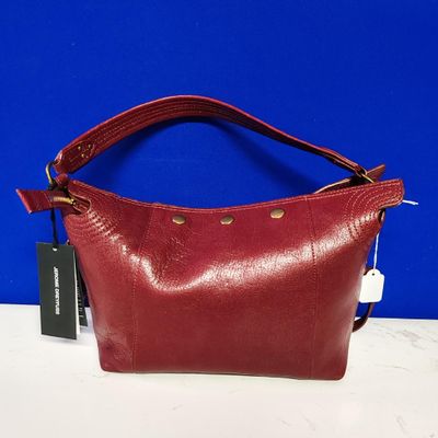 un sac à main rouge muni d'une étiquette, posé sur une table