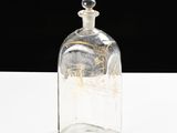 a clear glass bottle with a gold design on it