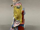figurine of a woman sitting on a bench with a basket on her head