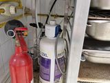 a red fire extinguisher and a white fire extinguisher in the corner of a kitchen