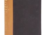 un vieux livre à la couverture noire posé sur une surface blanche