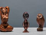 three bronze statues of a woman and an owl on a table