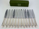 six silverplated knives and a box of knives on a table