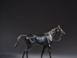 bronze statue of a horse on a wooden base against a gray background