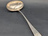 cuillère en argent avec un long manche, posée sur une surface noire