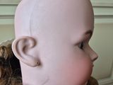 a doll that is wearing a wig with a tie around it ' s neck