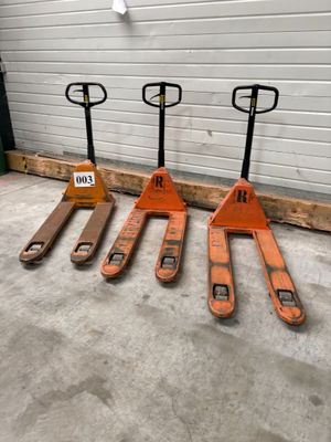 Trois chariots élévateurs orange sont alignés devant la porte d'un garage