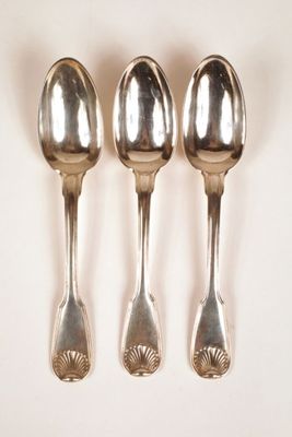 three silver spoons are lined up in a row on a white surface