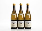 three bottles of white wine sitting next to each other on a white surface