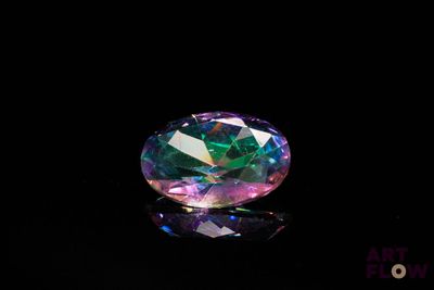 un gros plan d'un diamant rose et vert sur une surface noire