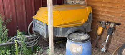 a yellow truck that is parked next to a blue barrel
