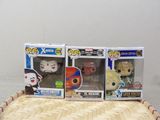 trois figurines Funko Pop en vinyle posées sur une table en bois