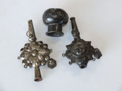 trois objets métalliques sont posés sur une surface blanche