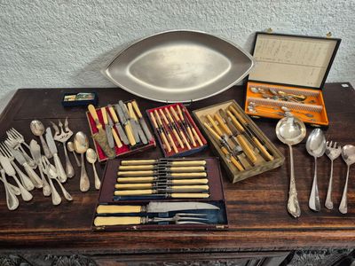 a lot of silverware on a table with a tray of forks and spoons