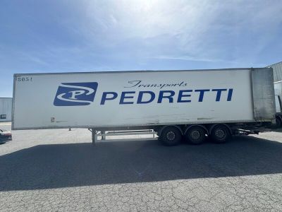 Le semi-remorque est garé sur le parking à côté du bâtiment.