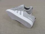 grey and white adidas sneakers with white soles on a beige surface