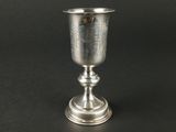 gobelet en argent posé sur une surface noire, avec un fond noir