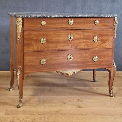 une commode en bois avec un plateau en marbre, posée sur un parquet en bois dur