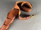 an old leather belt with a metal buckle on a gray surface