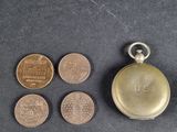 plusieurs pièces de monnaie et une montre de poche posées sur une surface noire
