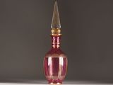 a pink glass bottle with a gold top on a table