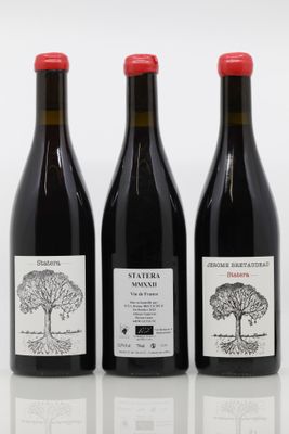 trois bouteilles de vin posées les unes à côté des autres sur une surface blanche